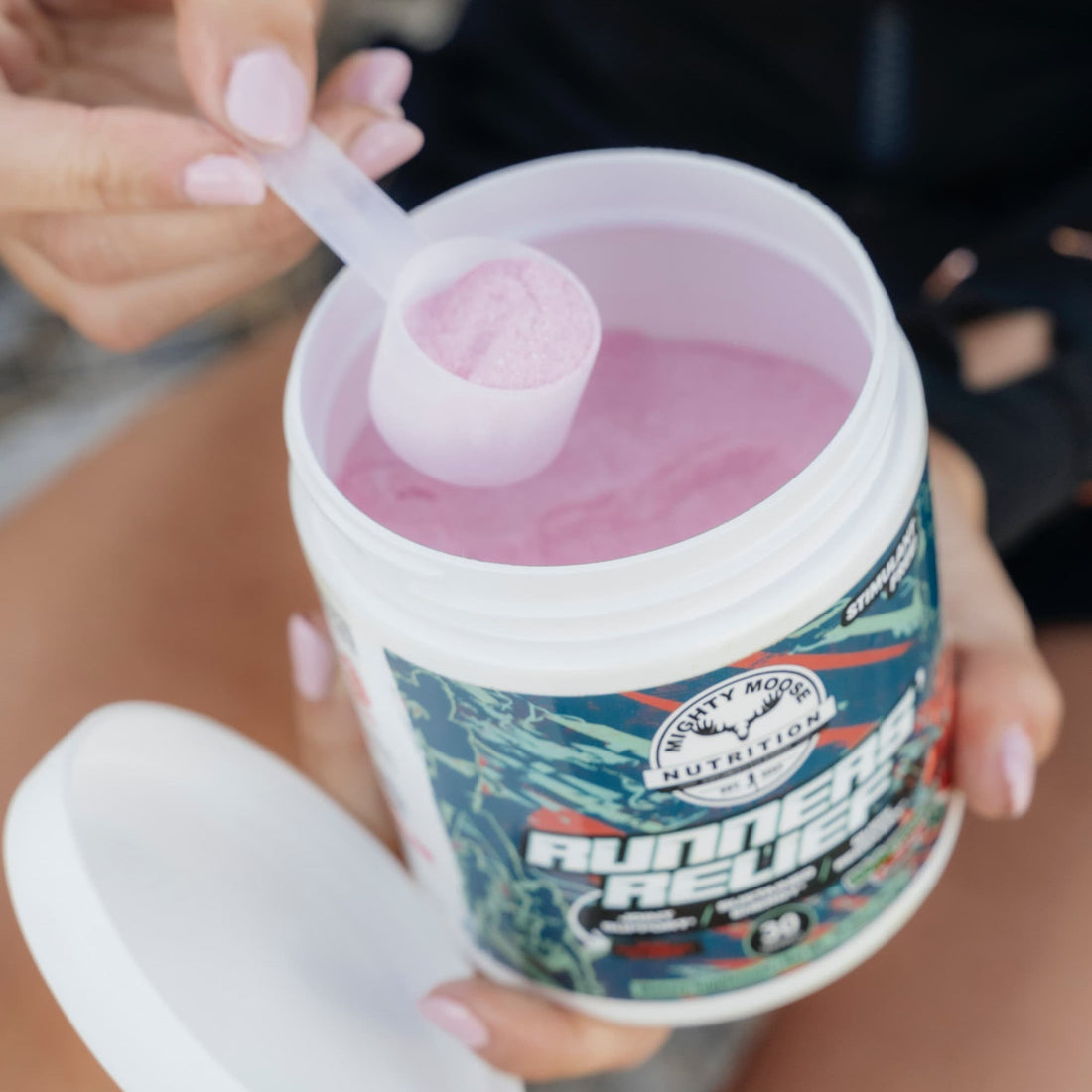 A runner outdoors with a tub of Runners' Relief recovery mix after a long run