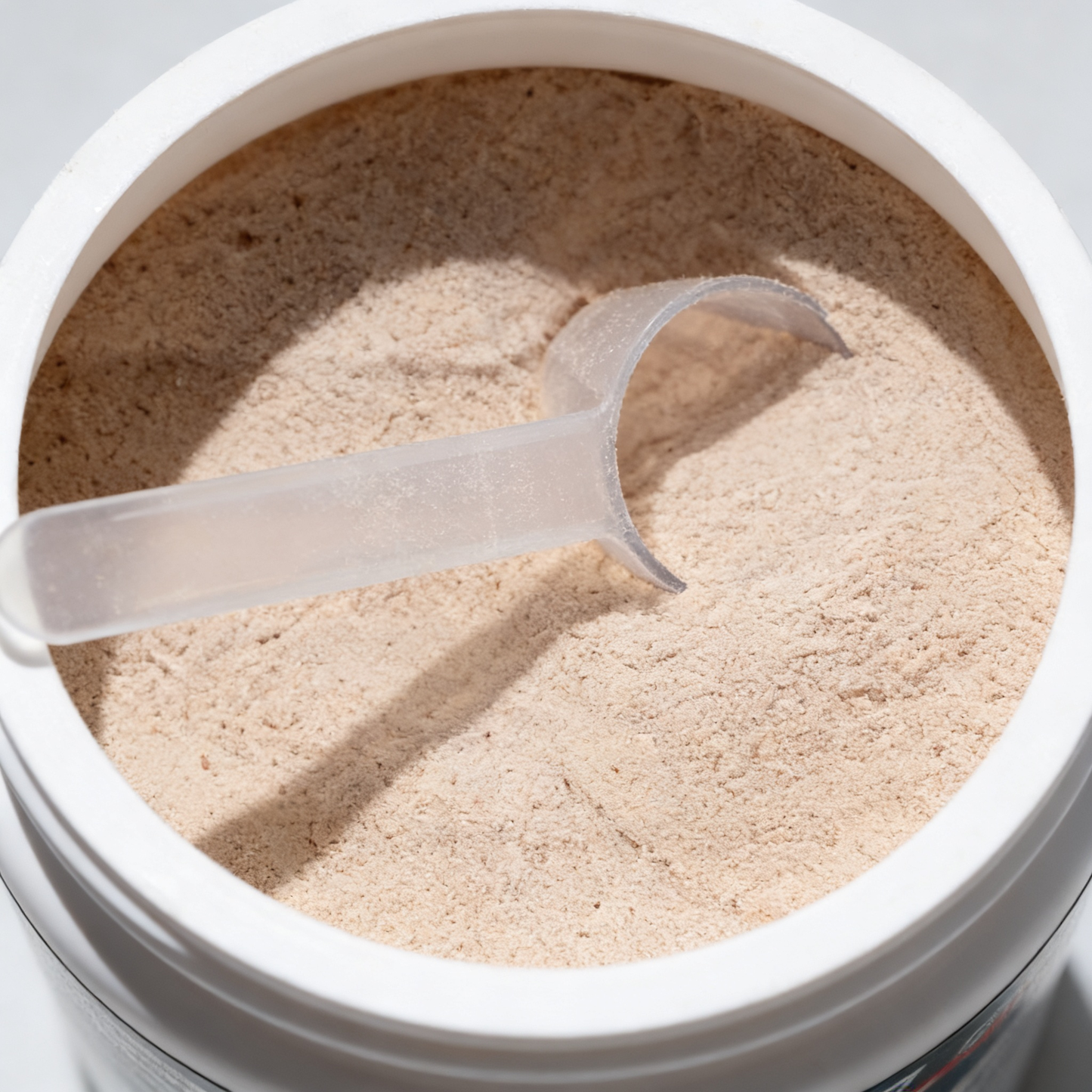 Open container of powder with a scoop inside, on a light gray background