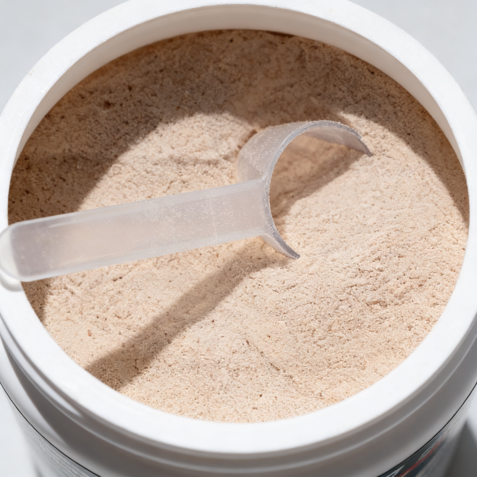 Open container of powder with a scoop inside, on a light gray background